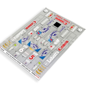May include: A sticker sheet for a LEGO set of a Williams FW14B race car. The sheet includes stickers for the car's sponsors, including Camel, Elf, Labatt's, and Canon. The sheet also includes numbers 5 and 6.