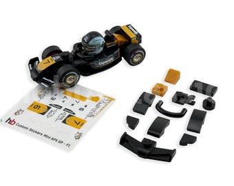 May include: A black and yellow miniature race car with a driver in a helmet. The car has the number 7 on it. Includes a sheet of custom stickers and several black and tan car parts.