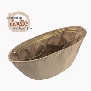 May include: Beige fabric bag organizer with multiple pockets and a gold zipper. The bag organizer is designed for a "Jodie" bag, which is a mini-teen-S-M size.