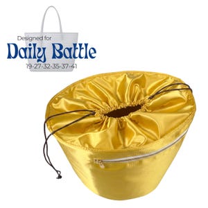 May include: A golden yellow drawstring bag with a white zipper and a white tote bag in the background. The text "Designed for Daily Battle" is above the bag, with numbers below.