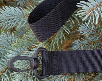 May include: Black adjustable strap with a metal hook and a plastic buckle. The strap is made of a woven nylon material.