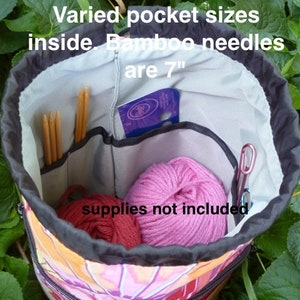 May include: A colorful drawstring bag with multiple pockets inside. The bag is open, revealing a variety of compartments and supplies, including bamboo knitting needles that are 7 inches long. "Varied pocket sizes inside. Bamboo needles are 7" "