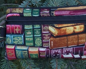May include: A black zippered pouch with a colorful print of stacked books. The books have gold lettering and are in various colors, including red, green, and brown.
