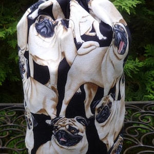 May include: A black drawstring bag featuring a pattern of pugs. The pugs are depicted in various poses and are printed in shades of brown and white.