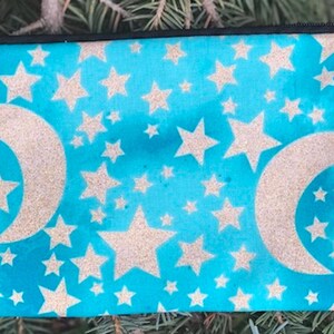 May include: A blue zippered pouch with a white glitter pattern of stars and crescent moons.