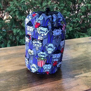 May include: A purple and grey drawstring bag with a pattern of cartoon vampires drinking from cups and eating popcorn.
