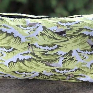 May include: A green and white zippered pouch with a repeating pattern of stylized waves and seagulls.