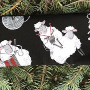 May include: Black zippered pouch with a white sheep pattern. The sheep are knitting yarn balls and holding knitting needles.