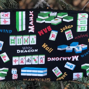 May include: Black zippered pouch with a Mahjong tile pattern. The design includes tiles, dice, and the words "Mahjong," "Wind," "White Dragon," and "Joker." The tiles are green, white, and blue.