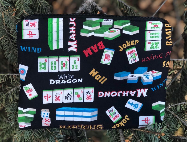 May include: Black zippered pouch with a Mahjong tile pattern. The design includes tiles, dice, and the words "Mahjong," "Wind," "White Dragon," and "Joker." The tiles are green, white, and blue.