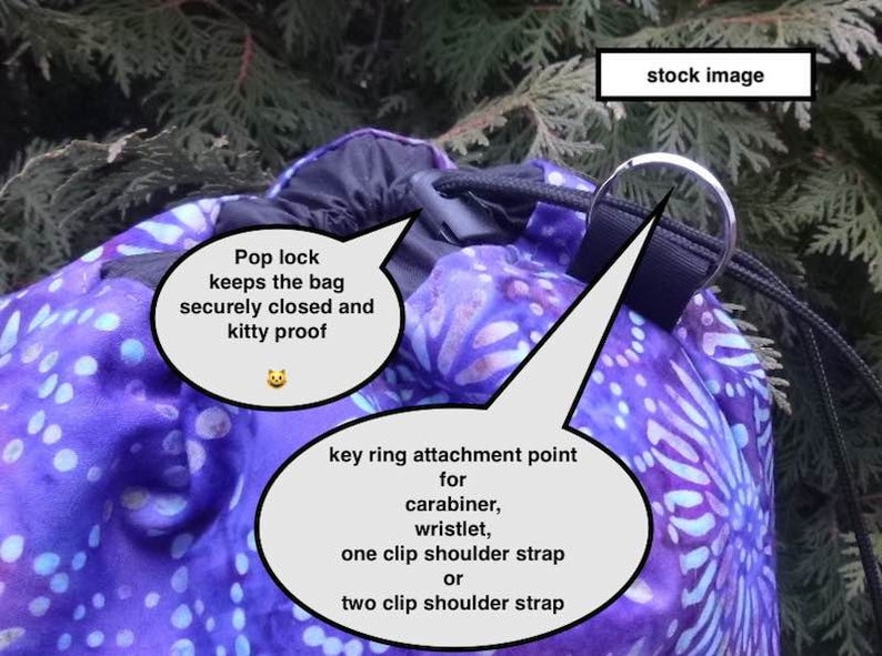 May include: A purple and blue drawstring bag with a pop lock closure. The bag has a key ring attachment point for a carabiner, wristlet, or shoulder strap. The text "Pop lock keeps the bag securely closed and kitty proof" is written on a white speech bubble.