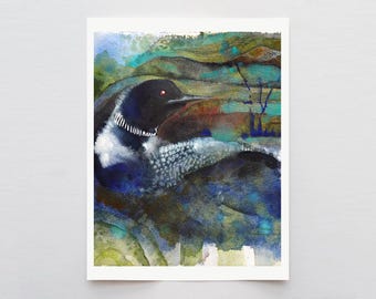 May include: Watercolor painting of a loon bird with a black head, white and black neck markings, and a red eye. The bird is set against a backdrop of blue, green, and brown watercolor washes. The artwork is on a white rectangular paper.