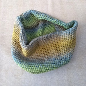 Può includere: Un collo a maglia all'uncinetto in tonalità di verde, blu e marrone. Il collo è realizzato con un punto testurizzato e ha una vestibilità rilassata e morbida.