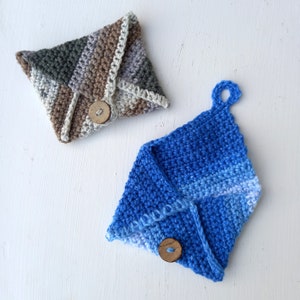 May include: Two crocheted pot holders with wooden buttons. One is brown, green, and white, and the other is blue with a gradient to white.