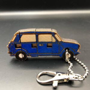 May include: A blue wooden car keychain with a silver chain. The car is made of wood and has a blue paint finish. The keychain is a fun and unique way to add personality to your keys.