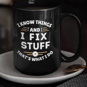 May include: Black coffee mug with white text that reads "I know things and I fix stuff that's what I do". The text is surrounded by a gold-colored graphic of a wrench and a saw blade.