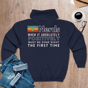 May include: Navy blue sweatshirt with a retro-style graphic that says "Nerds When It Absolutely Positively Must Be Done Right The First Time". The graphic features a green hand and a rainbow-colored background.