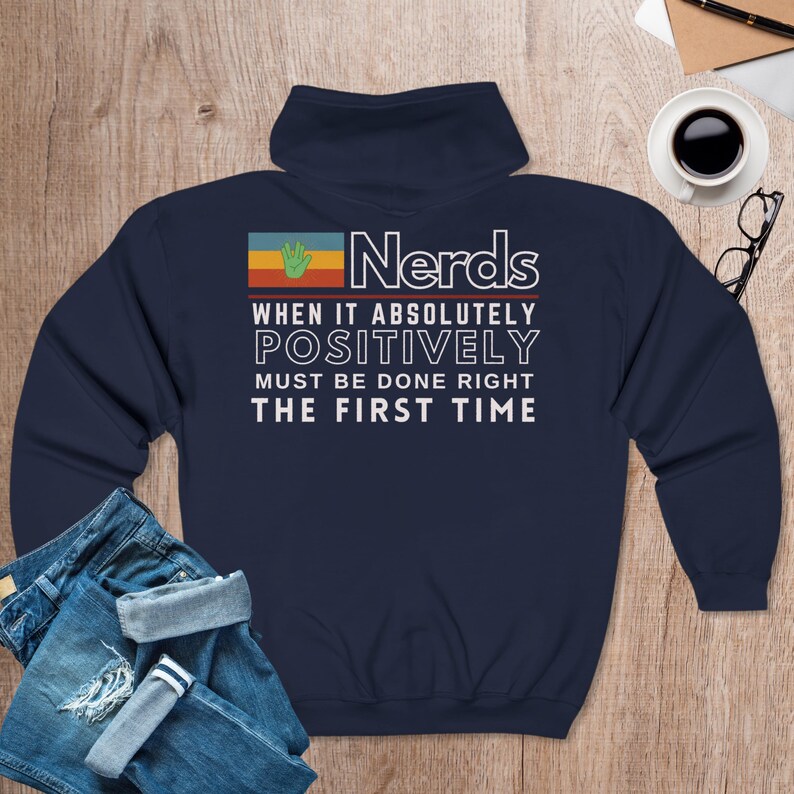May include: Navy blue sweatshirt with a retro-style graphic that says "Nerds When It Absolutely Positively Must Be Done Right The First Time". The graphic features a green hand and a rainbow-colored background.