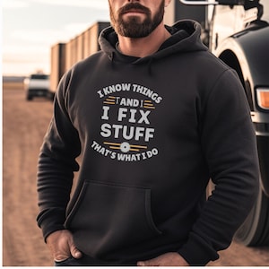 May include: Black hooded sweatshirt with a white graphic print that reads "I know things and I fix stuff that's what I do". The graphic also includes a stylized saw blade.