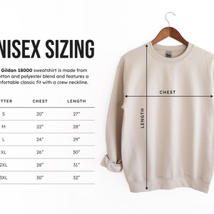 May include: Unisex sizing chart for a Gildan 18000 sweatshirt. The chart shows the chest and length measurements in inches for sizes S, M, L, XL, 2XL, and 3XL. The chart is next to a beige sweatshirt with a crew neckline.
