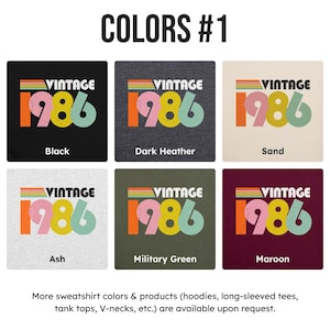 May include: Image displaying six t-shirt colour options: black, dark heather, sand, ash, military green, and maroon. Each shirt features the text "VINTAGE 1986" in a retro design with colourful stripes.
