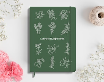 Może przedstawiać: Zielona książka kucharska z białym obramowaniem różnych ziół i przypraw na okładce. Tytuł "Laurens Recipe Book" jest nadrukowany na przodzie na biało.