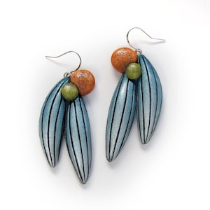 May include: A pair of silver dangle earrings with blue and silver striped teardrop-shaped charms. Each earring has a small orange and green bead.