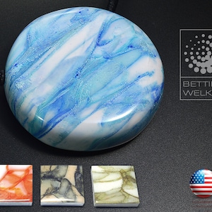 May include: A round, blue and white marbled pendant with a black cord. The pendant is made of resin and has a glossy finish. The pendant is 5 cm in diameter. The pendant is part of a collection of marbled resin pendants.