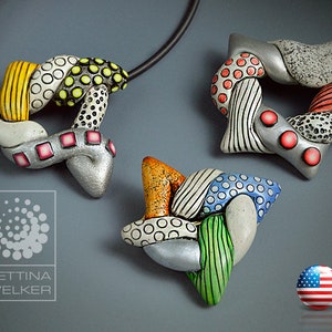 May include: Three colorful ceramic pendants with intricate designs. Each pendant features a different combination of geometric shapes, stripes, dots, and swirls in various colors, including white, black, red, yellow, green, blue, and silver.
