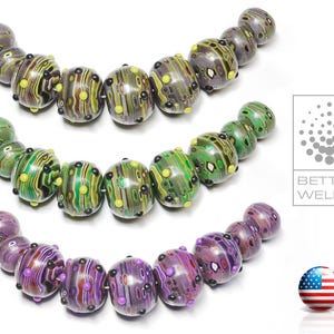 Puede incluir: Tres hileras de cuentas de vidrio de colores con un patrón de mármol. Las cuentas están dispuestas en forma de semicírculo. Las cuentas son verdes, moradas y amarillas con detalles en blanco y negro.