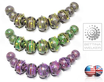 May include: Three strands of colorful glass beads with a marbled pattern. The beads are arranged in a semi-circle shape. The beads are green, purple, and yellow with black and white accents.