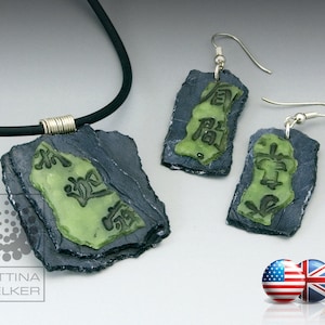 Peut inclure: Un collier noir avec un pendentif en ardoise à plusieurs niveaux orné de caractères chinois verts. Boucles d'oreilles assorties en ardoise et caractères chinois verts.