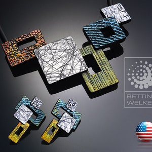May include: A colorful ceramic necklace and earrings set with geometric shapes. The necklace features a black cord with five interlocking squares in various colors and patterns, including orange, yellow, blue, white, and black. The earrings are a smaller version of the necklace design.