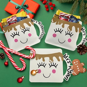 以下が含まれることがあります： 茶色と金色の絵付けが施された白いセラミック製のマグカップが3つ。黒いまつげ、ピンクの頬、笑顔の口で飾られています。それぞれのマグカップには、「ロバートソン夫人」、「トーマス夫人」、「メイソン夫人」という名前が書かれています。