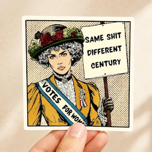 Puede incluir: Una pegatina cuadrada con una ilustración pop art de una persona con sombrero de flores y chaqueta amarilla, con una banda azul que dice VOTES FOR WOMEN. La persona sostiene un cartel que dice SAME SHIT DIFFERENT CENTURY sobre fondo punteado.