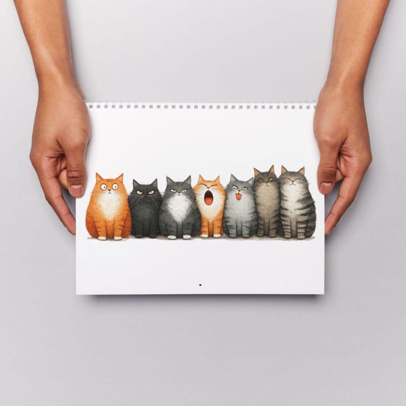 May include: A spiral-bound notepad featuring a row of seven cartoon cats with various expressions. The cats are in shades of orange, black, gray, and brown. The notepad is held by two hands against a white background.