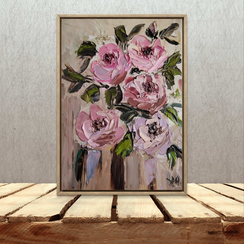 Puede incluir: Una pintura enmarcada de un ramo de rosas rosas con hojas verdes sobre un fondo beige.