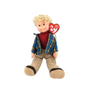 May include: A plush doll of a boy with curly blonde hair, wearing a red sweater, khaki pants, and a blue and yellow plaid jacket. The doll has a red heart-shaped tag attached.