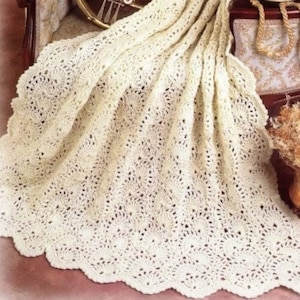 May include: A white crocheted blanket with a scalloped edge, draped over a chair with a gold French horn and a small cup and saucer.