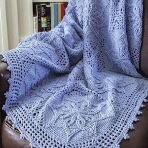 May include: A light blue crocheted throw blanket with a delicate floral pattern, draped over a brown leather armchair.