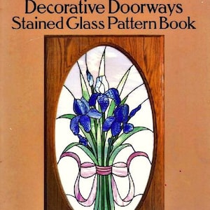 May include: Book cover with a stained glass pattern of a bouquet of blue irises with pink ribbons in a wooden frame. The title of the book is "Decorative Doorways Stained Glass Pattern Book" and the subtitle is "151 Designs for Sidelights, Fanlights, Transoms, etc." The author is Carolyn Relei.