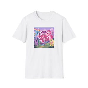 May include: White t-shirt featuring a colorful graphic of cartoon ponies with a rainbow and the text "My Little Panic Attack". The design includes various ponies and a castle in the background. The shirt is made of a soft material.