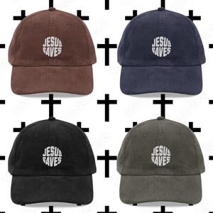 Könnte beinhalten: Vier Cord-Baseballkappen in Braun, Marineblau, Schwarz und Olivgrün. Jede Kappe hat den gestickten Text "JESUS SAVES" in einem kreisförmigen Design. Die Kappen werden vor einem weißen Hintergrund mit einem Muster aus schwarzen Kreuzen gezeigt.