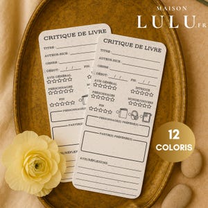 Peut inclure: Deux cartes de critique de livre beiges avec le texte "CRITIQUE DE LIVRE" et des sections d'évaluation. Les cartes sont sur une assiette dorée avec une fleur jaune et le texte "12 COLORIS".
