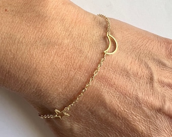 Puede incluir: Un brazalete de cadena dorada con un dije de media luna y estrella.