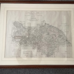May include: A framed vintage map of Yorkshire, England, in a brown wooden frame. The map is printed in black and white and features detailed geographical information. The map includes text such as "England and Wales Combined Index" and "Yorkshire".