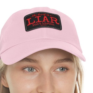 May include: A pink baseball cap with a black patch that says "The Devil's a LIAR Don't Listen".