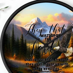 May include: A black wall clock with a scenic image of a mountain range, a river, and a bald eagle in flight. The clock face features the text "They that wait upon the Lord shall renew their strength; they shall mount up with wings as eagles... Isaiah 40:31".