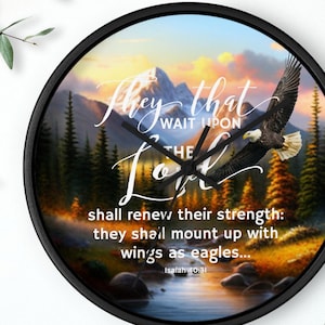 May include: Black-framed wall clock featuring a scenic mountain and river landscape with an eagle in flight. The clock face includes the text "They that wait upon the Lord" and a Bible verse. A decorative item.