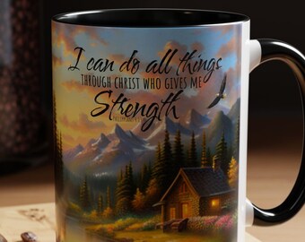 May include: White ceramic mug with a black handle and rim. The mug features a scenic image of a cabin in the woods with a quote that reads "I can do all things through Christ who gives me Strength - Philippians 4:13".